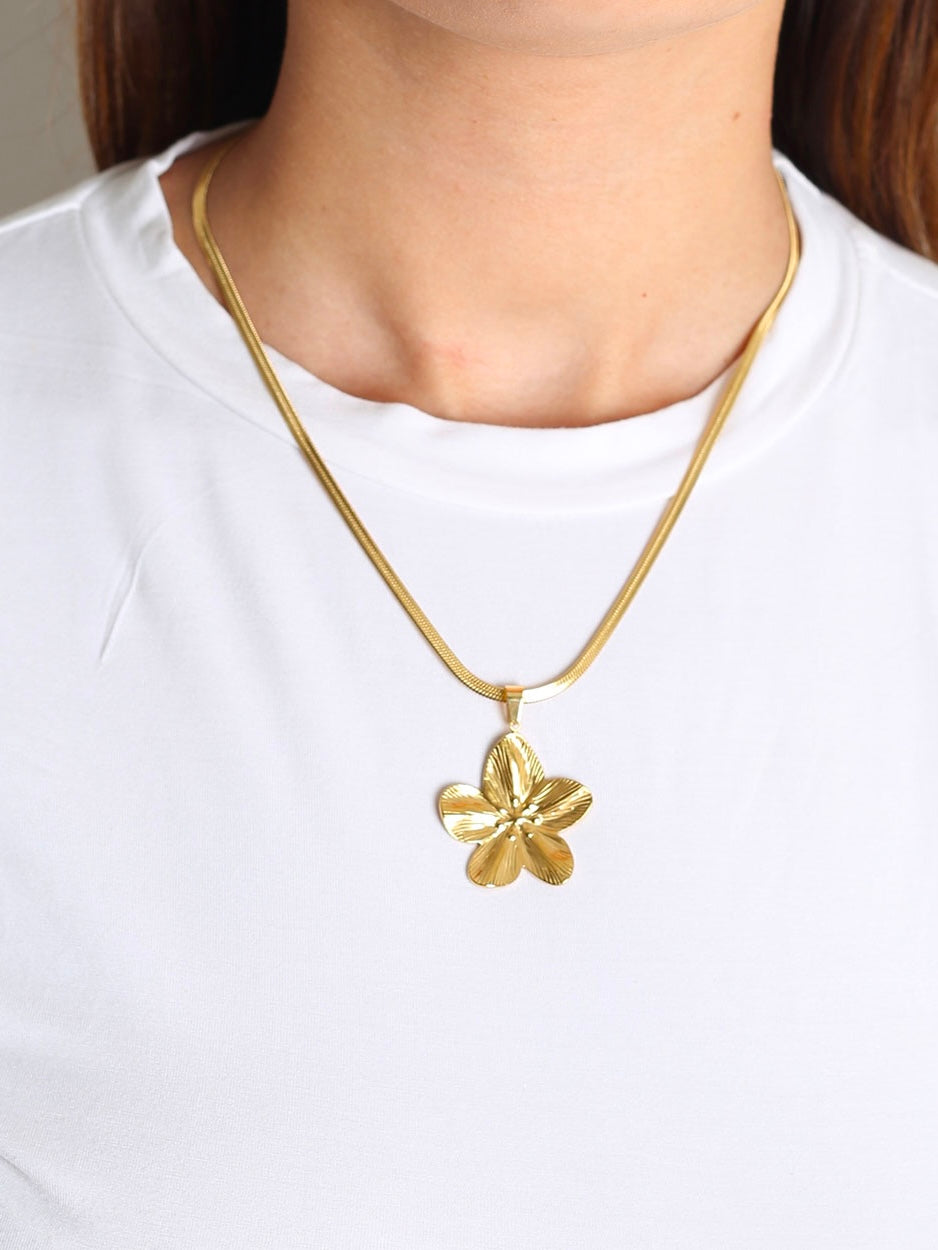Collana Flower di GLAMORIZE STUDIO con pendente floreale in metallo dorato e dettagli eleganti su sfondo neutro